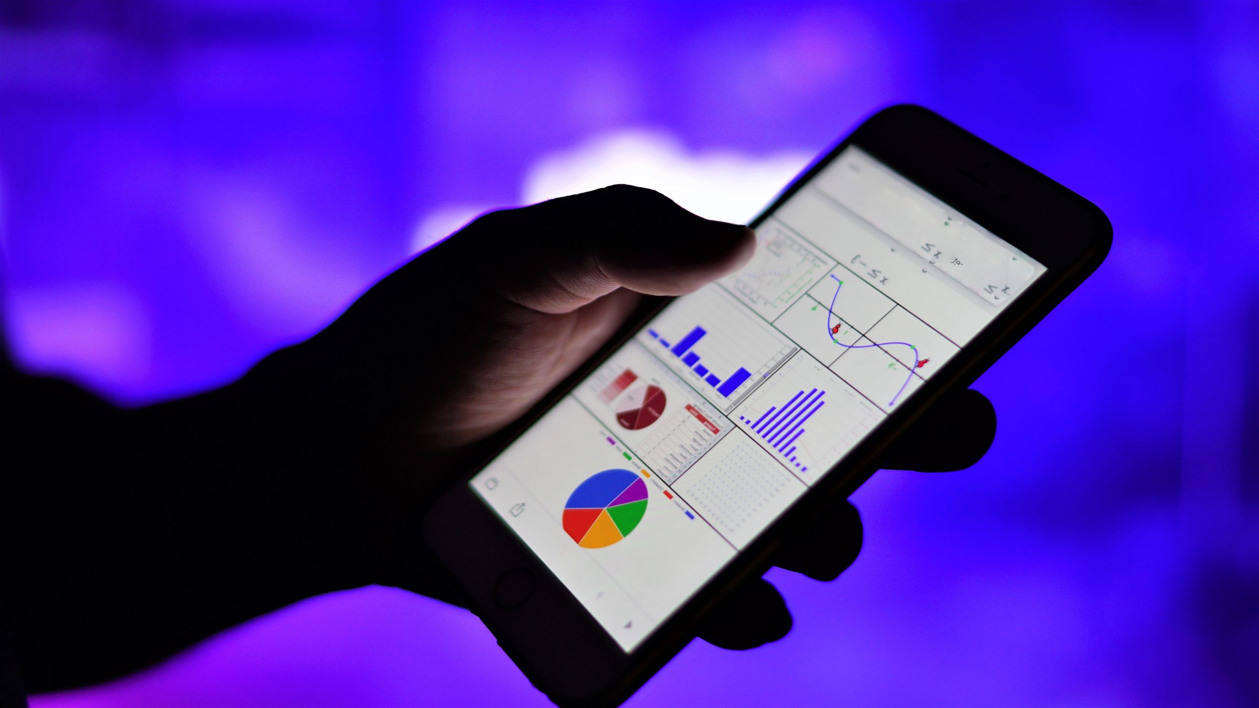 close up on hand holding smartphone showing graphs and charts on screen with blurred background t20 bAw2VP scaled