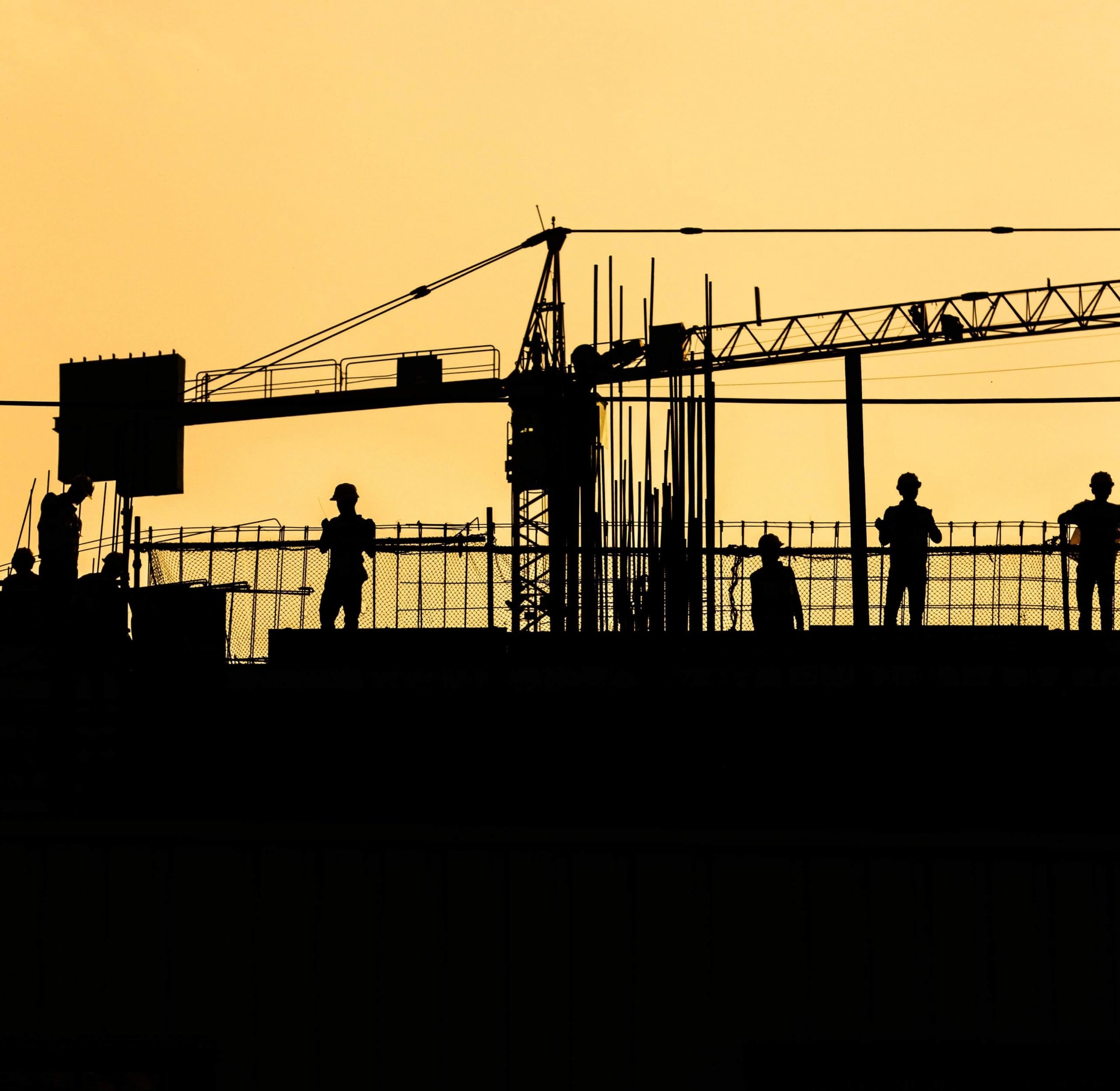 silhouette of construction site with yellow sunset in background
