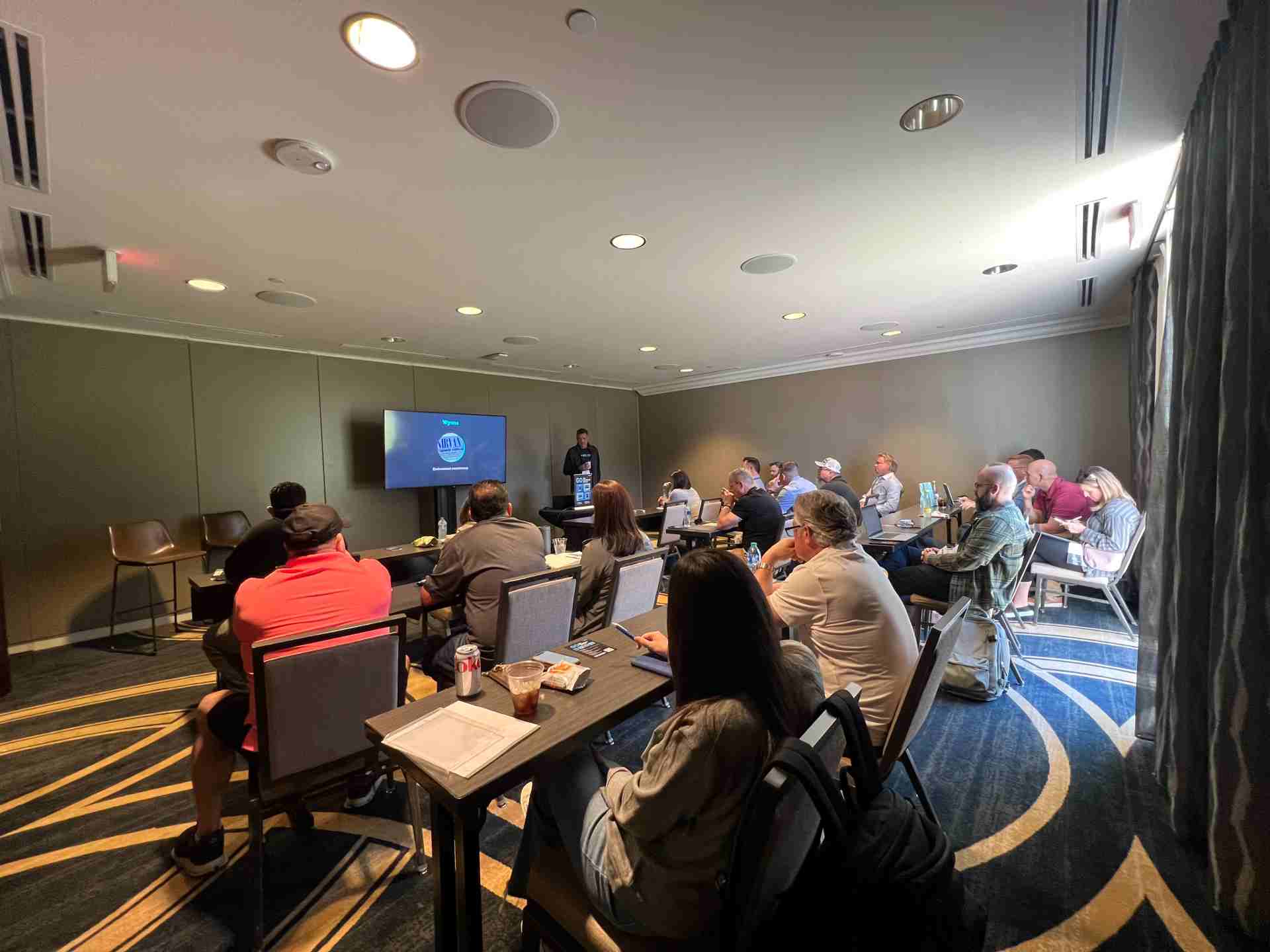 A group of professionals sitting at table in a conference room looking at a presentation